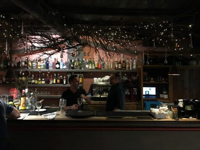 Bartenders Talking In A Bar With Bottles And Glasses