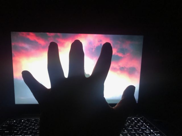 Hand In Front Of A Glowing Colorful Laptop Screen