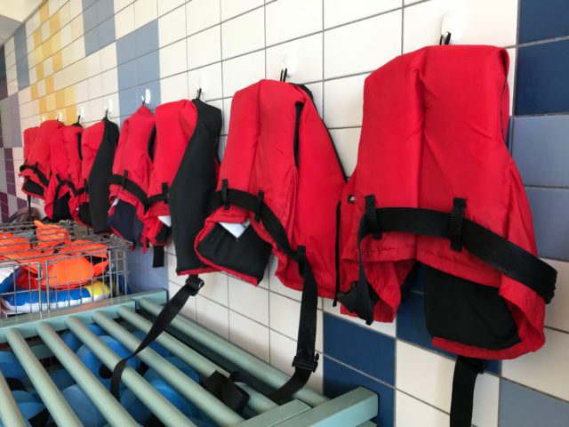 Lined Up Red Lifevests For Swimming On Wall Hangers