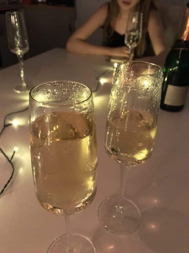 Glasses And Bottle Of Champagne With Table Lights
