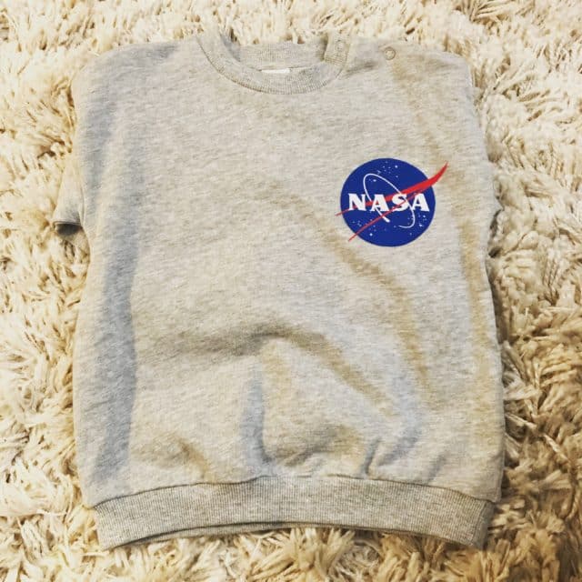 Gray Kid’s NASA Sweater Laying On A Rug