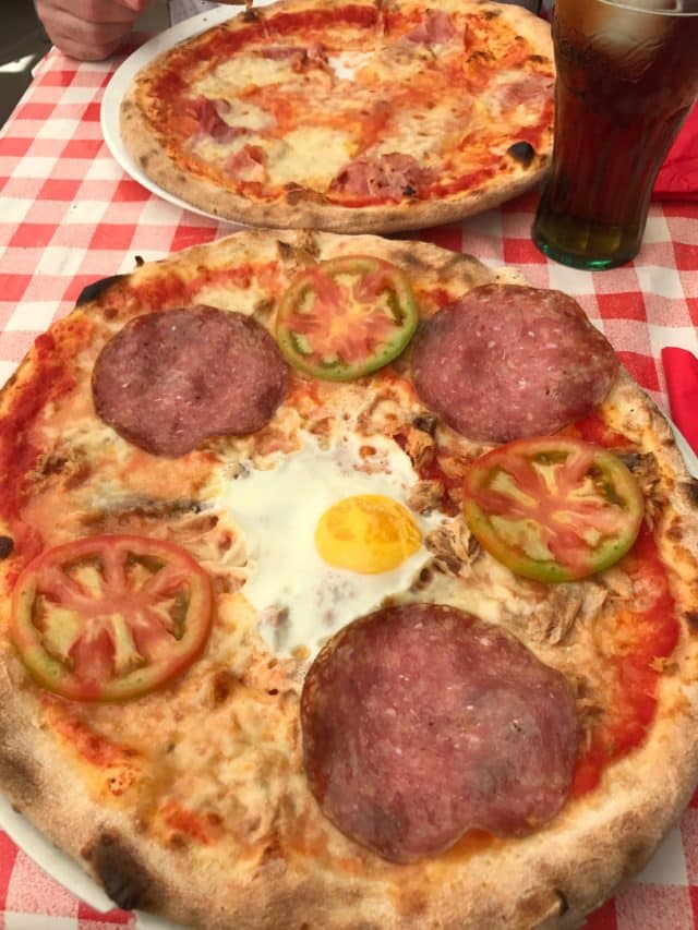 Pizzas With Salami And Eggs And Mozzarella On A Checkered Tablecloth With Drink