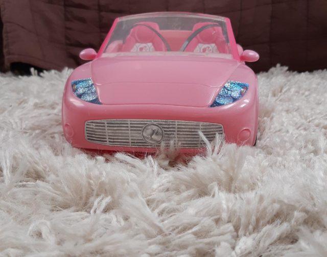 A Pink Barbie Convertible Car On A White Carpet