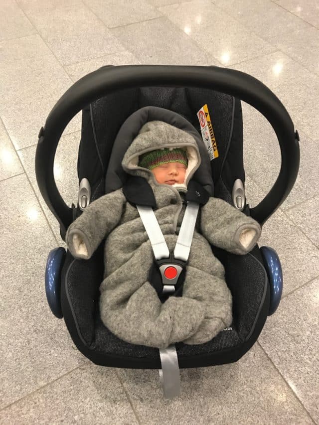 Newborn Boy In A Gray Winter Overall And Knitted Hat In Baby Car Seat