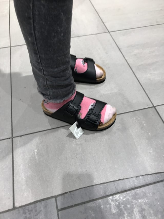 Slippers With Pink Socks And Black Jeans With A Light Gray Background