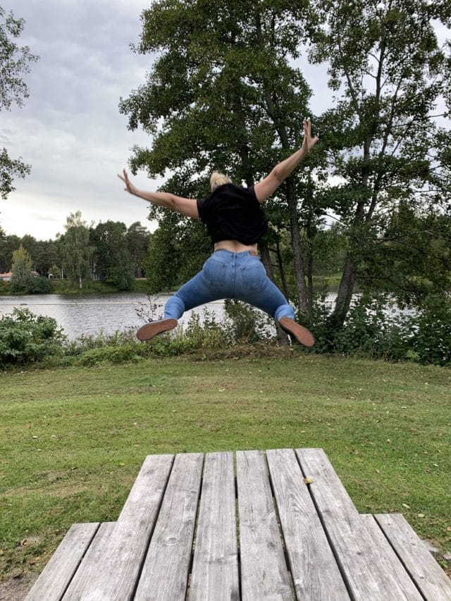 Woman In Black Shirt Jumping Off A Wooden Table