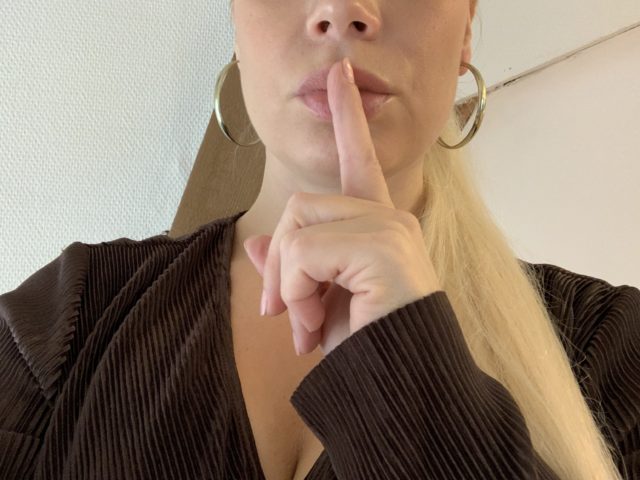 Woman holding Index Finger To Her Lips For Silence