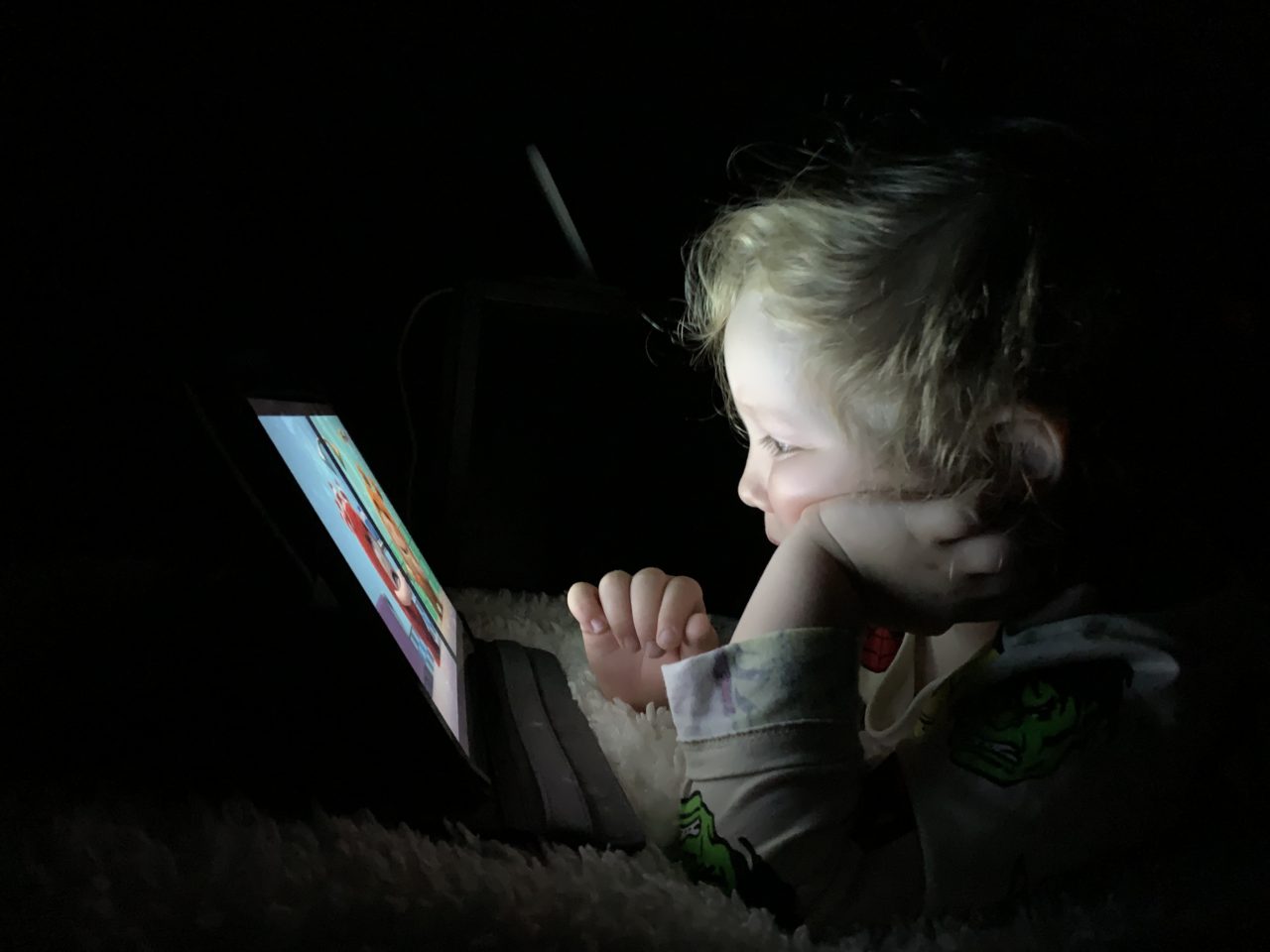 Kid Watching A Netflix Show On A Tablet In The Dark