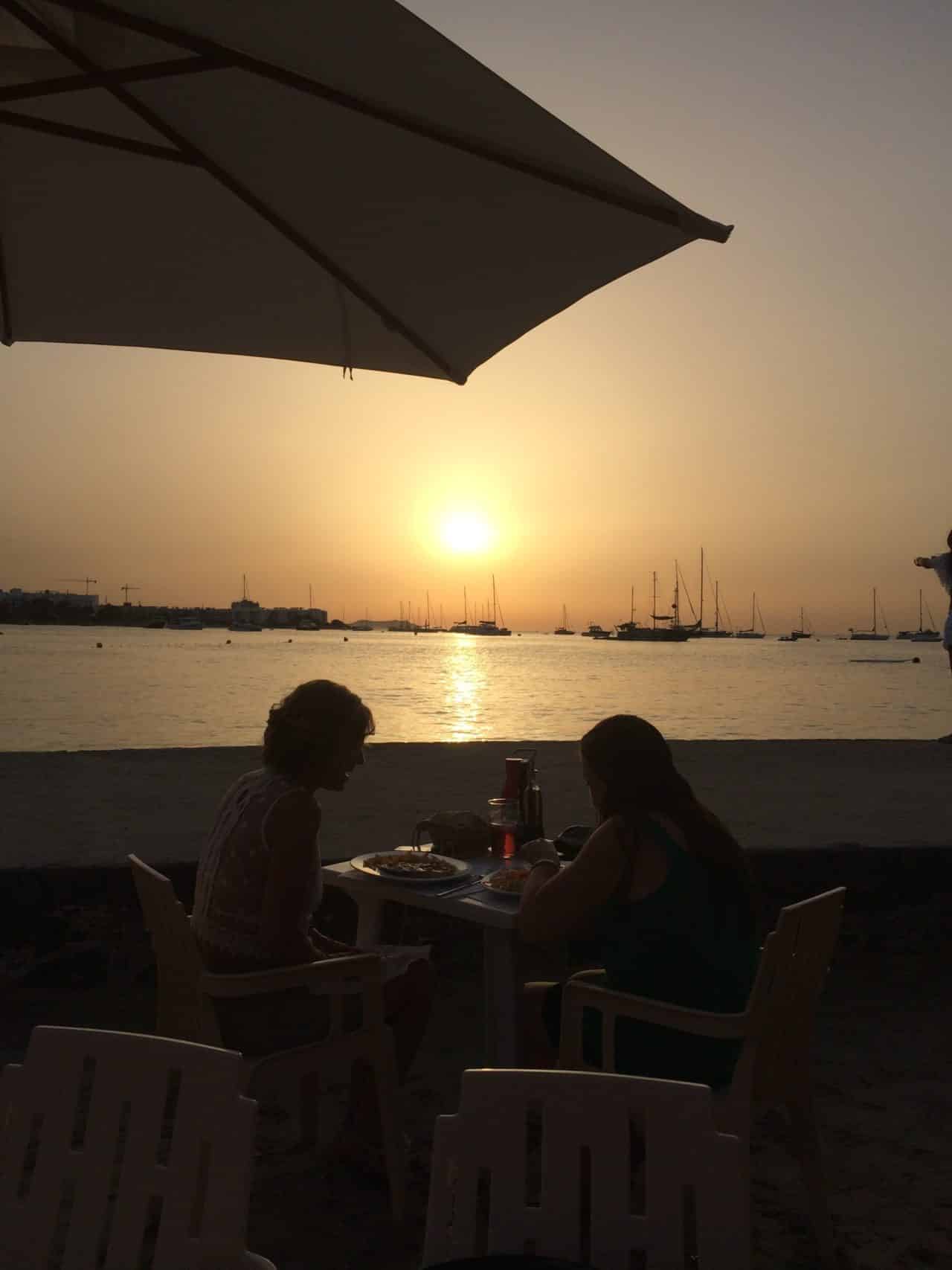 Sunset Dinner By The Sea With Boats And Umbrella