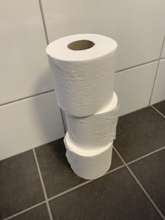 Stacked Toilet Paper Rolls On A Bathroom Floor