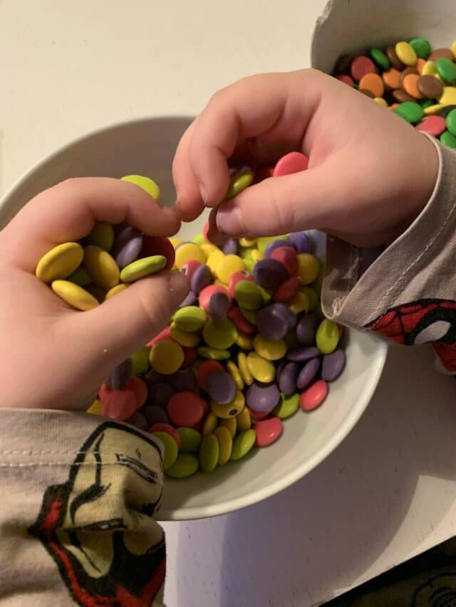 Child Holding Candy In Hands Over A Bowl
