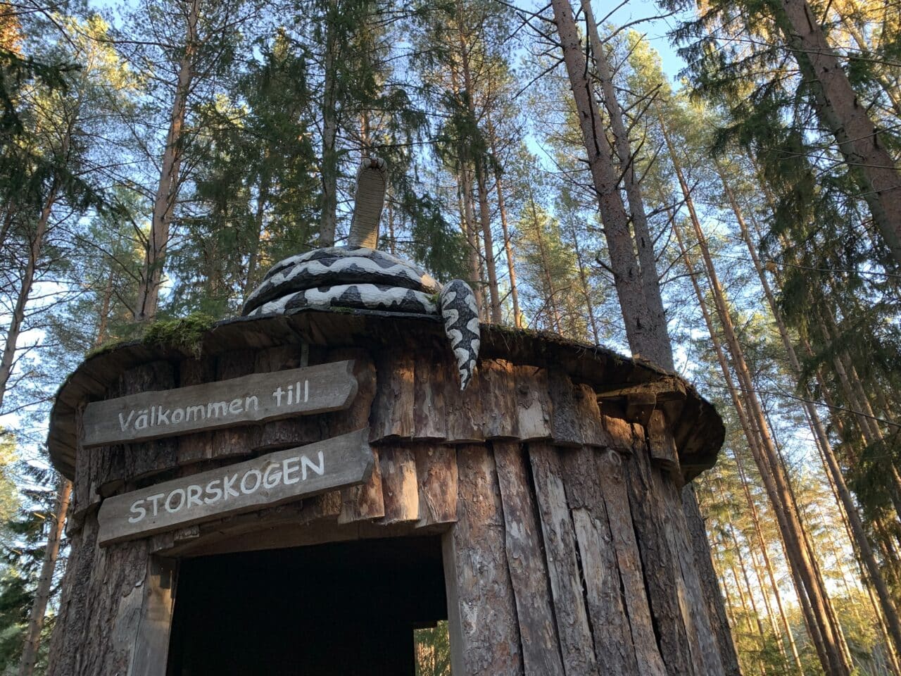 Forest Hut With Signs And Carved Wooden Snake On Top