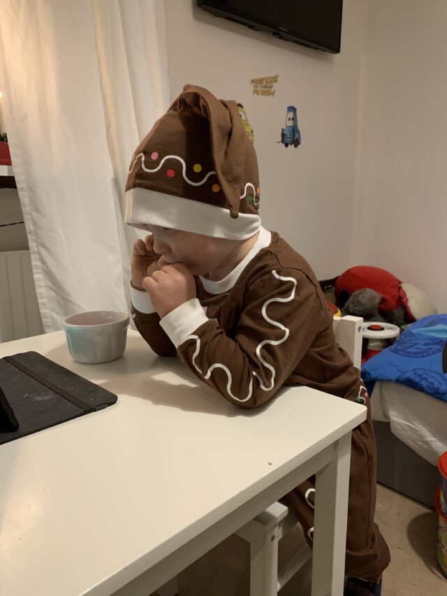 Child Waring Gingerbread Costume And Watching An iPad