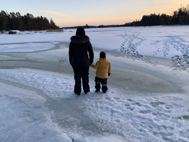 Mother Holding Child By The Hand By A Frozen Sea In Winter