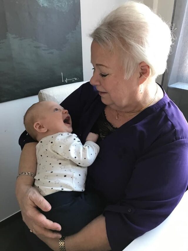 Elderly Woman Holding Newborn Baby In Arms