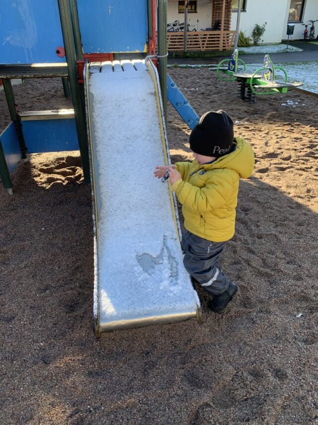 Child Playing At Playground Slide With Frost On It