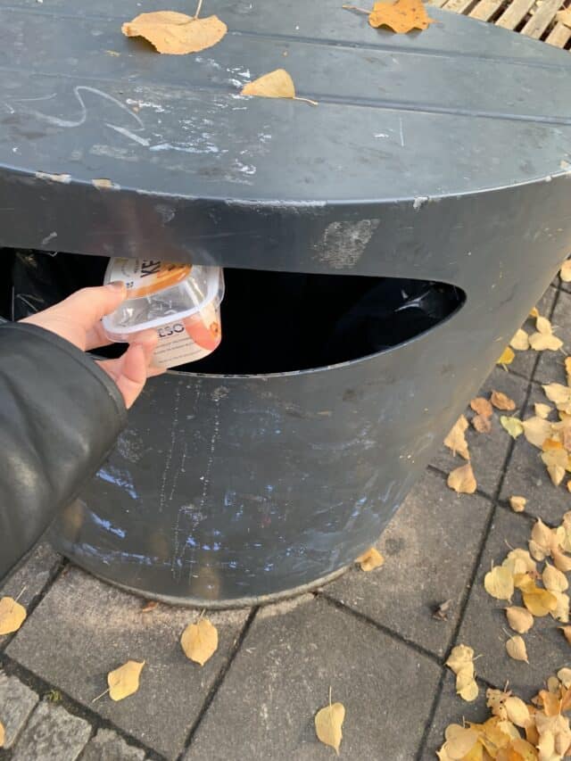 Throwing Away Trash In Public Trash Can