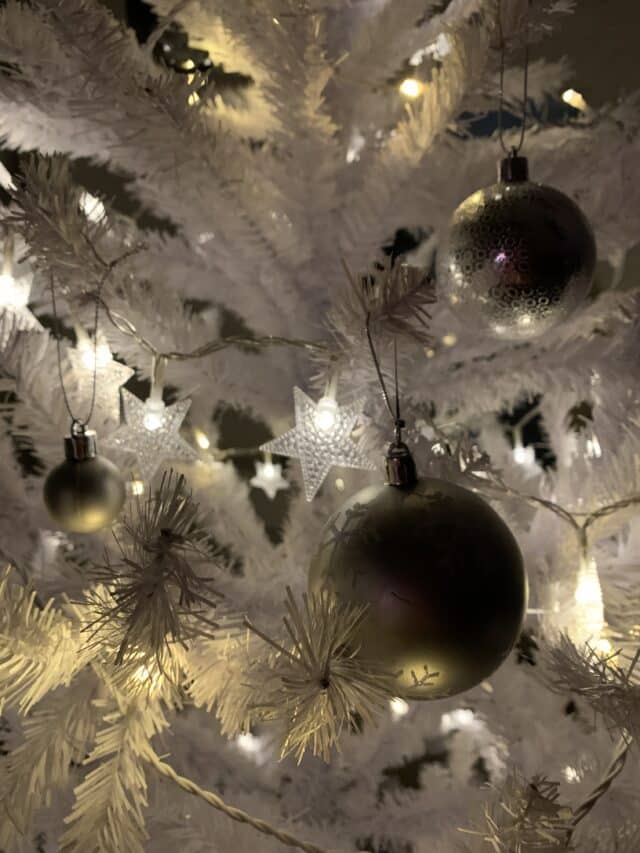 Silver Baubles In White Christmas Tree With Star Lights