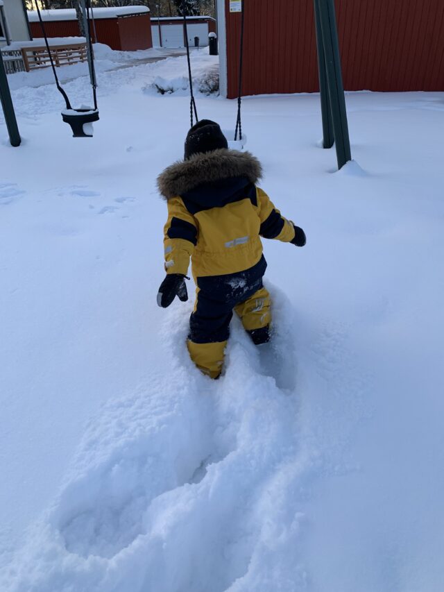 Child Walking In Deep Snow To A Swing Set At Winter