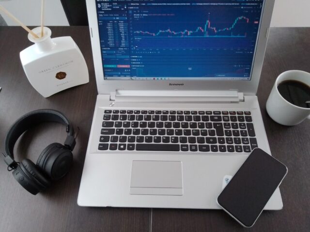 Laptop Screen With Crypto Trading Graph And iPhone